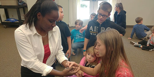 Undergraduate student, Constance Darrisaw, showing off a Chaco golden knee tarantula to some young visitors at the Belleview Public Library. 